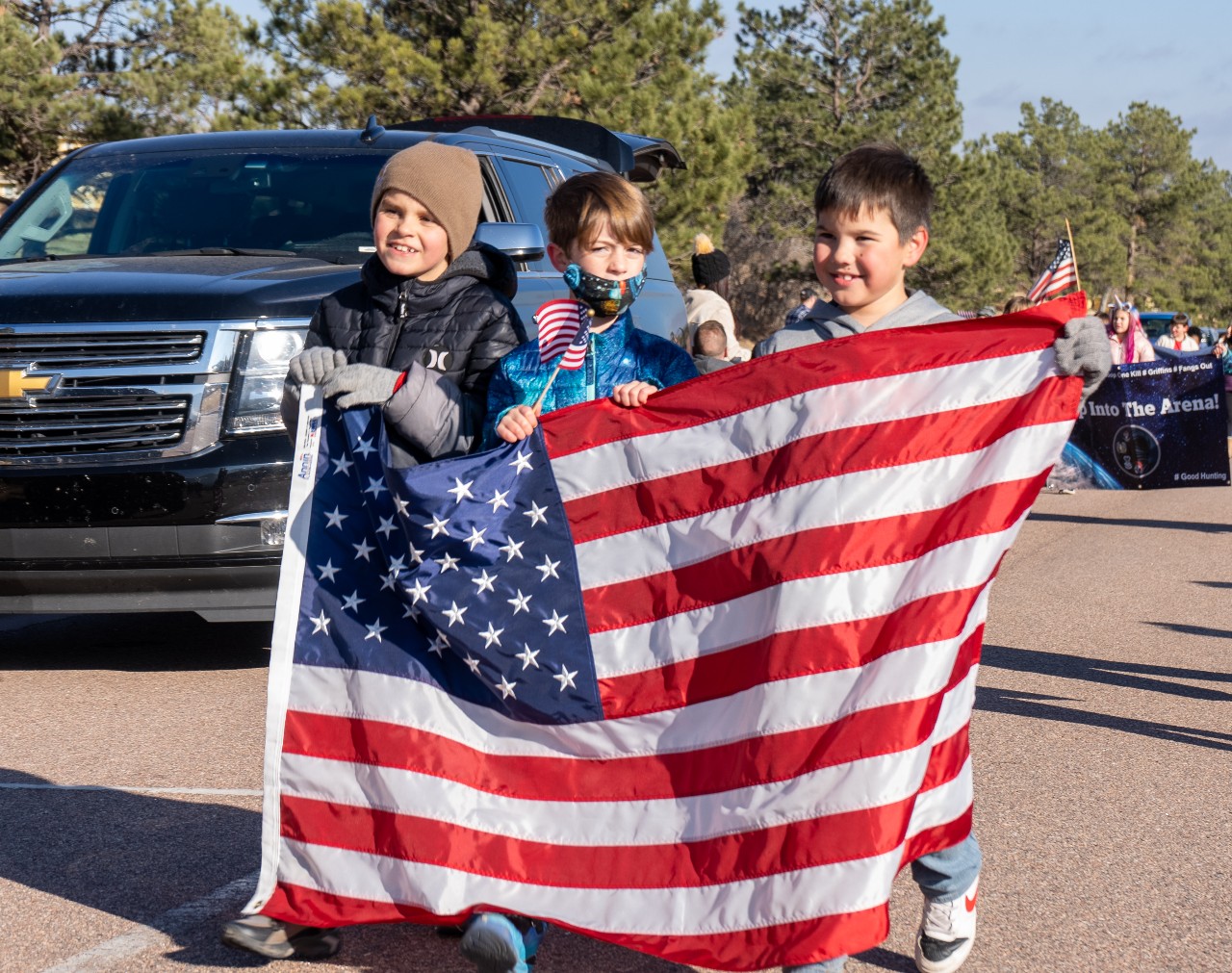 Three students carry the US flag during a Veterans Day parade.